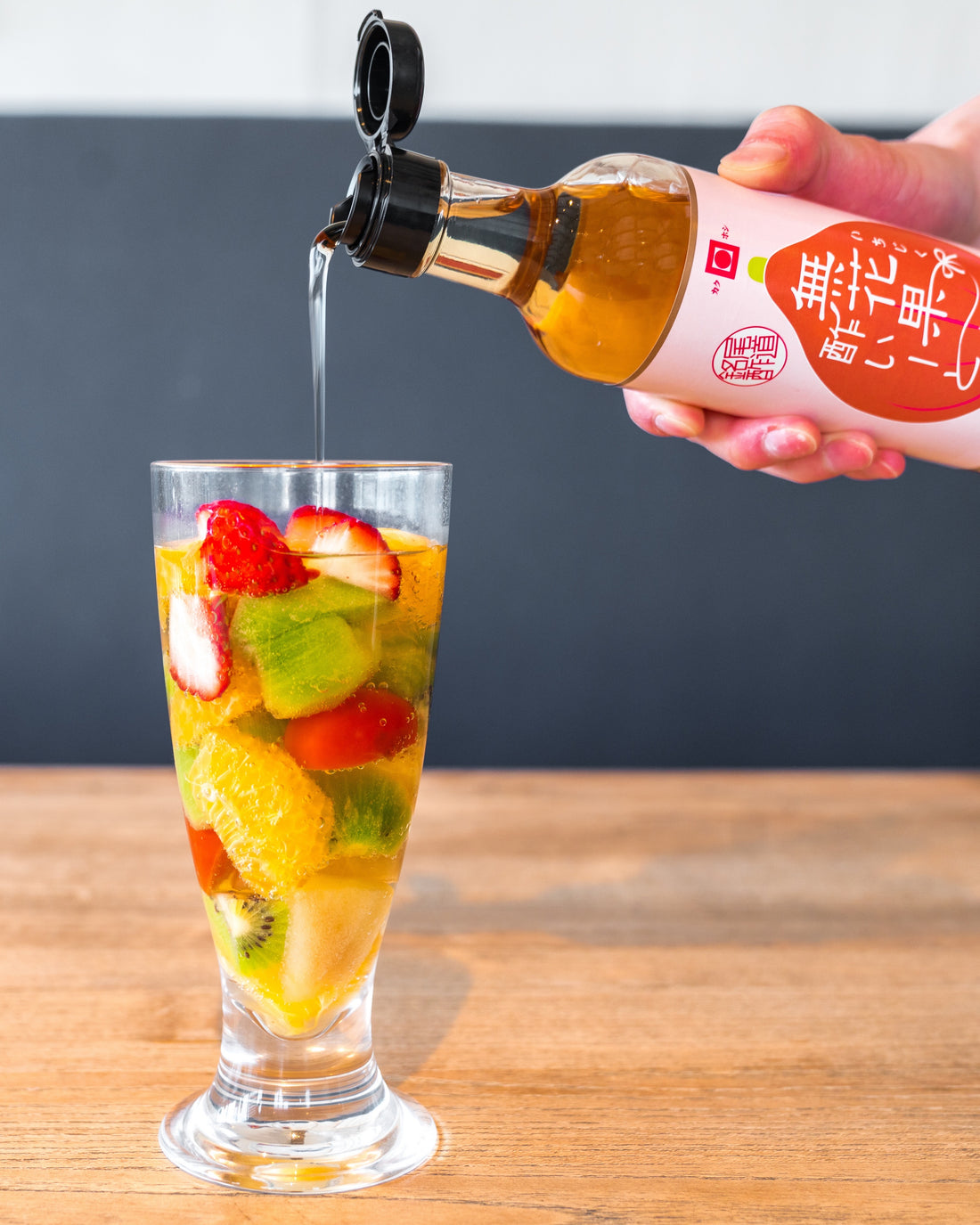 尾道造酢フルーツポンチビネガードリンク（飲む酢）の画像で果物が入ったグラスにいちじく酢いーとを注いでいる画像です。